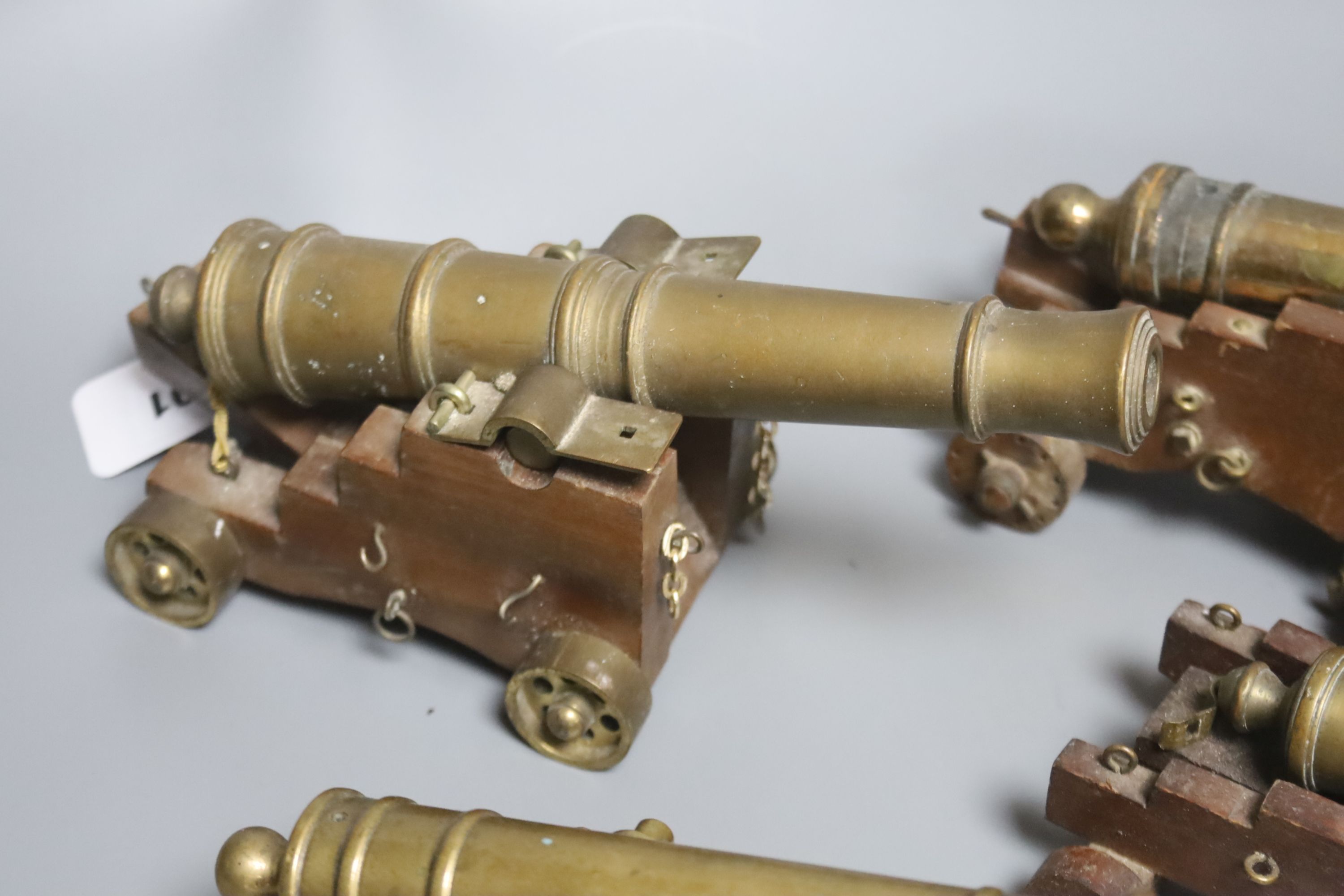 Four bronze or brass model cannons, with associated wood carriages, 20th century, barrel lengths 18-24.5cm